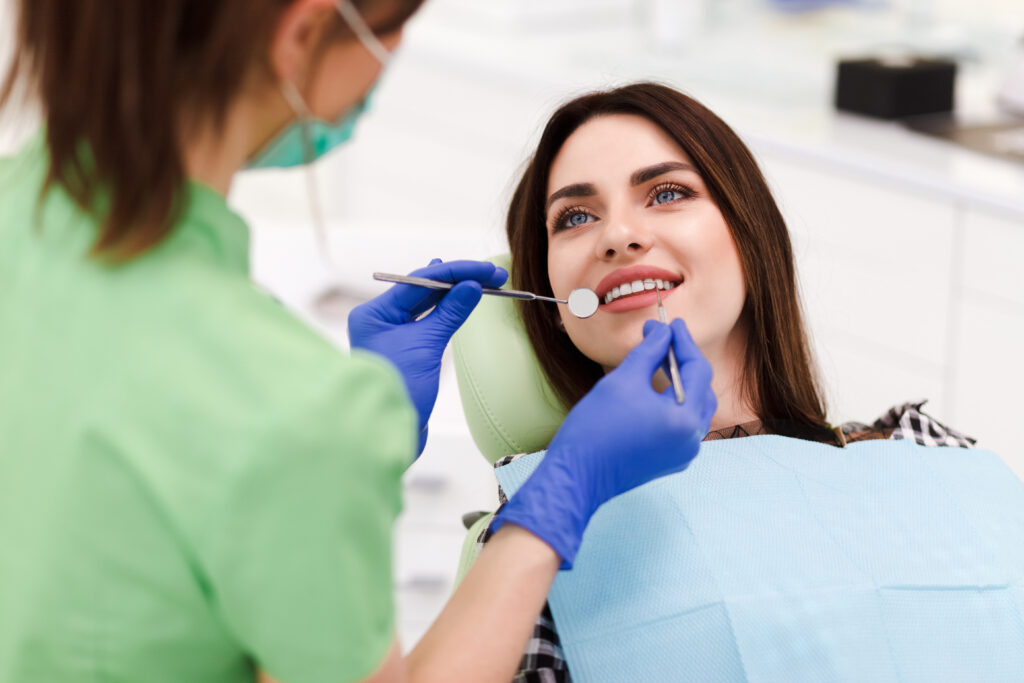 Beautiful young woman doing tooth examination in the dental office. Portrait of smiling girl on a dental chair in dentistry