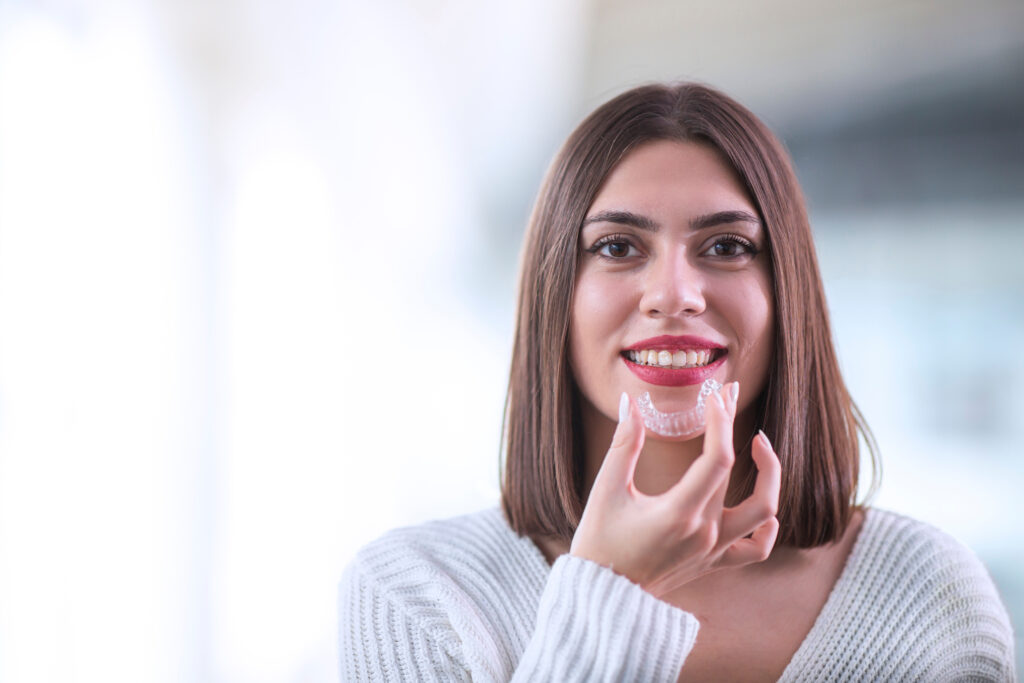 Beautiful smiling Turkish woman is holding an invisalign bracer, includes copy space
